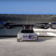 A photo of a flying car rolling out a large garage at an airfield.